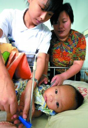 2008年9月13日，醫(yī)務人員為10個半月大的腎衰竭患兒換藥，該患兒因喝三鹿奶粉而患病。新華社記者 陳飛 攝
